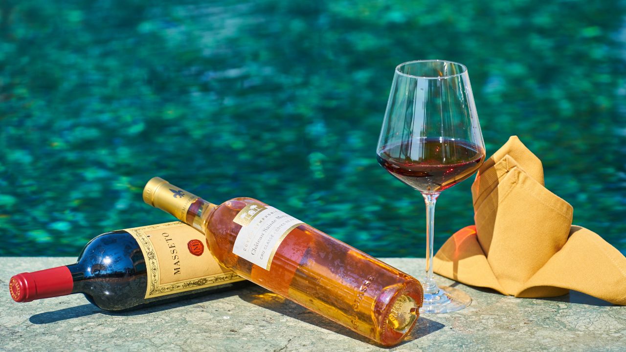 Two bottles of wine and a glass of wine by poolside| Hotel Package Ideas